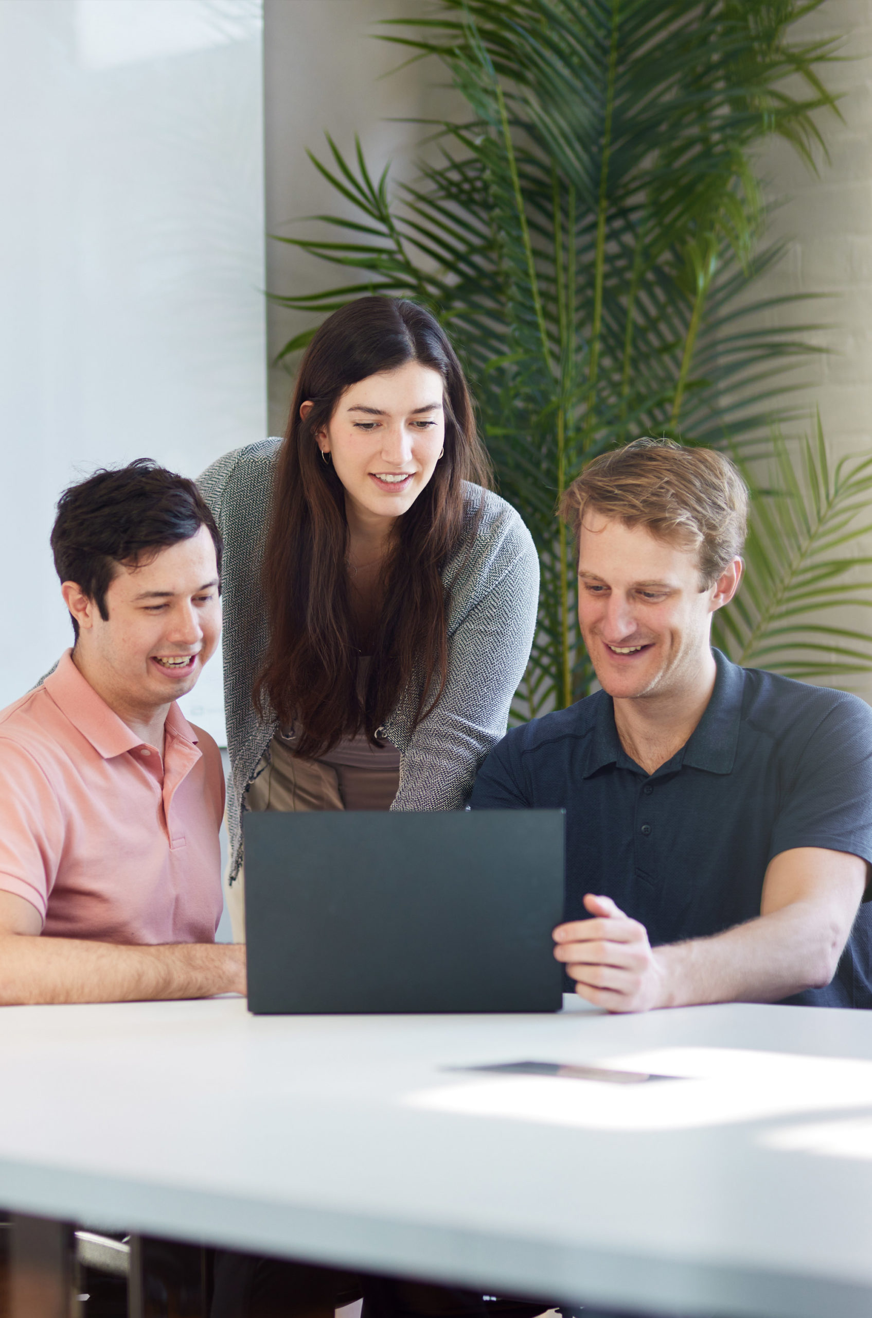 Two male office workers taking notes on a presentation while smiling