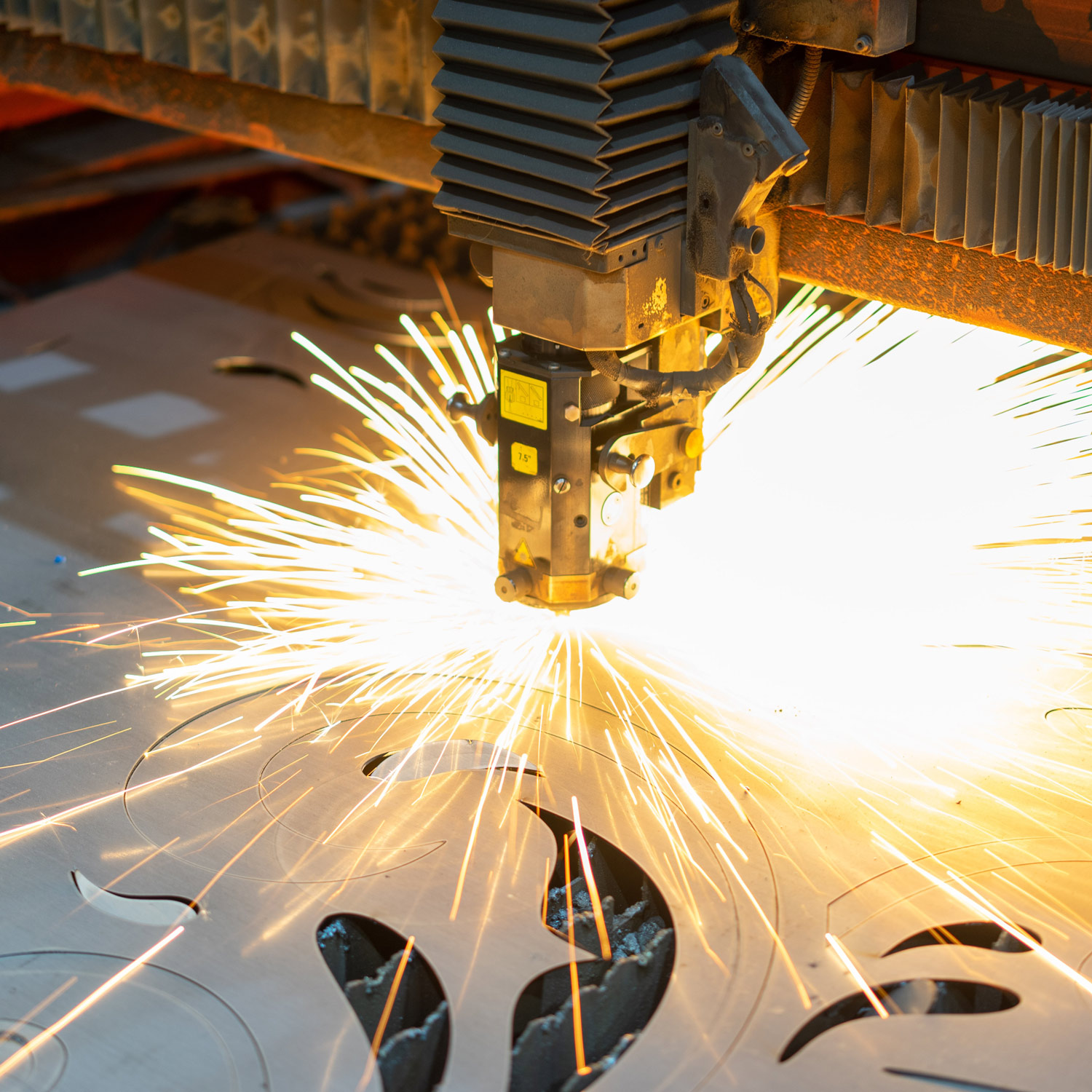 a CNC mill cutting designs into a sheet of metal